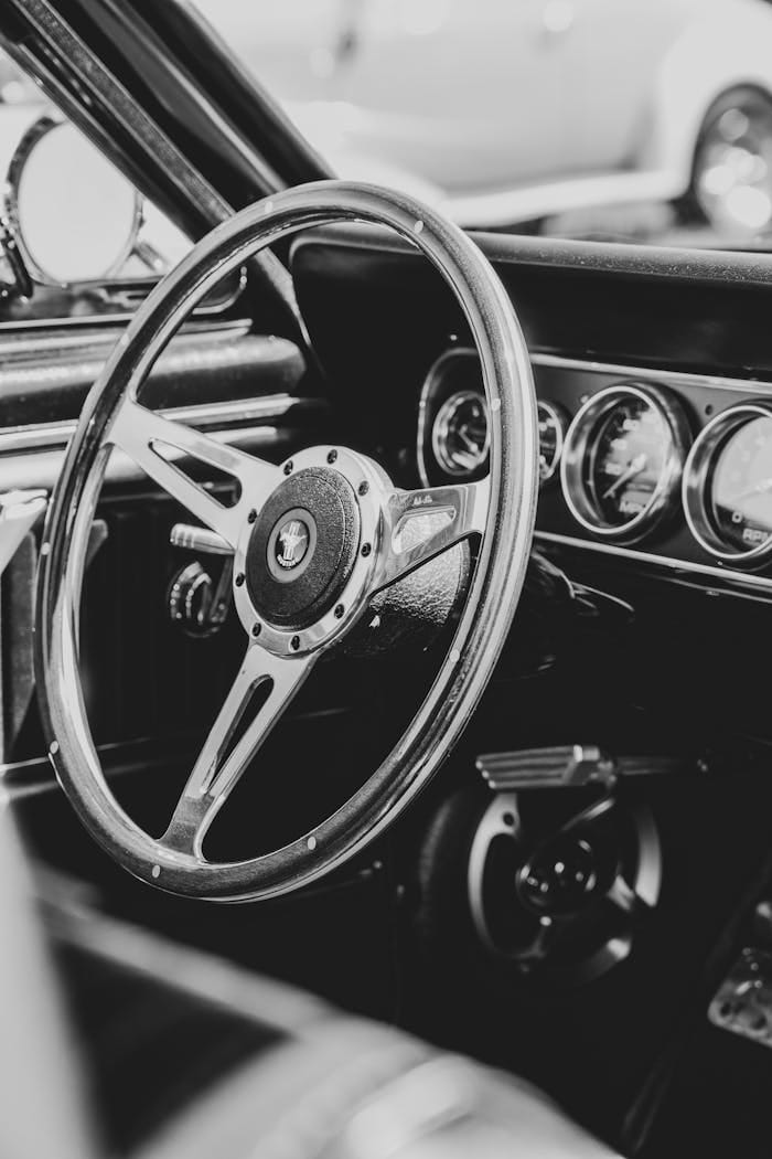 O nas Monochrome close-up of a classic car interior showcasing steering wheel and dials.